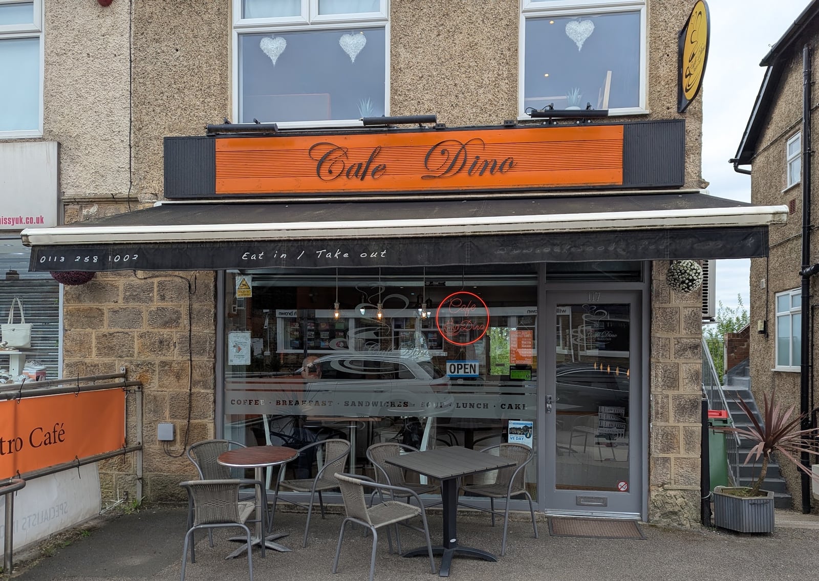 Cafe Dino's orange shopfront and outdoor tables at 117 New Road Side